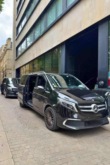 Van noir stationné devant un immeuble de bureaux moderne.