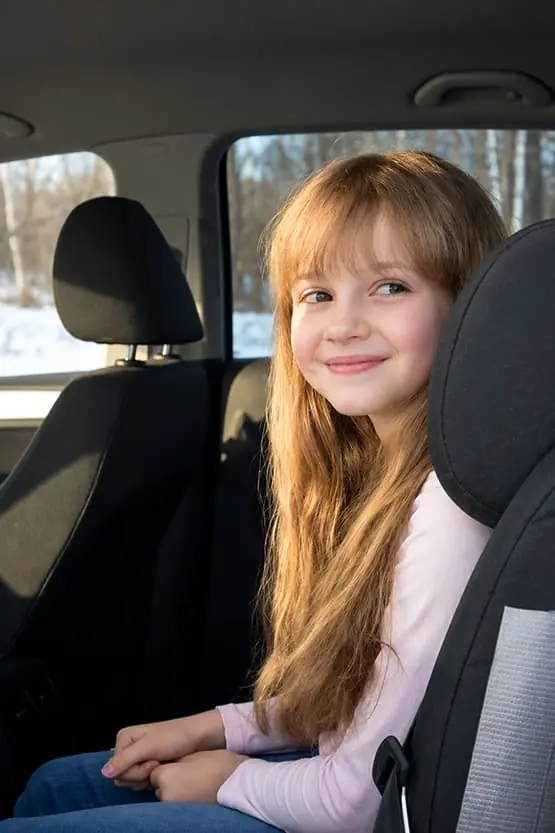 Jeune passagère attachée dans un siège auto à l’arrière d’un véhicule.